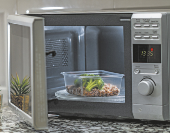 Fotografia de um recipiente de plástico contendo comida em um micro-ondas.