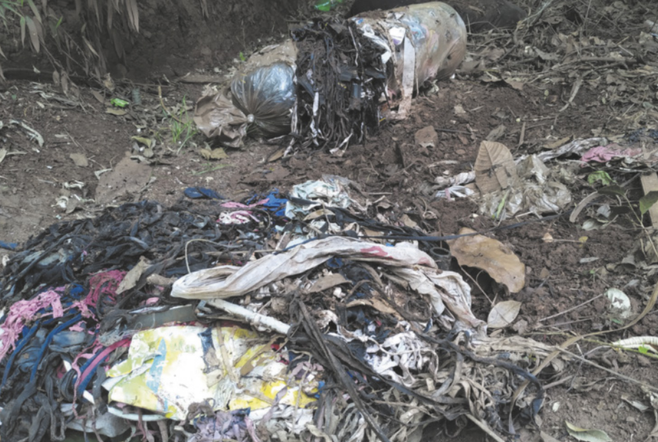 Fotografia de roupas destruídas, descartadas irregularmente em um terreno.