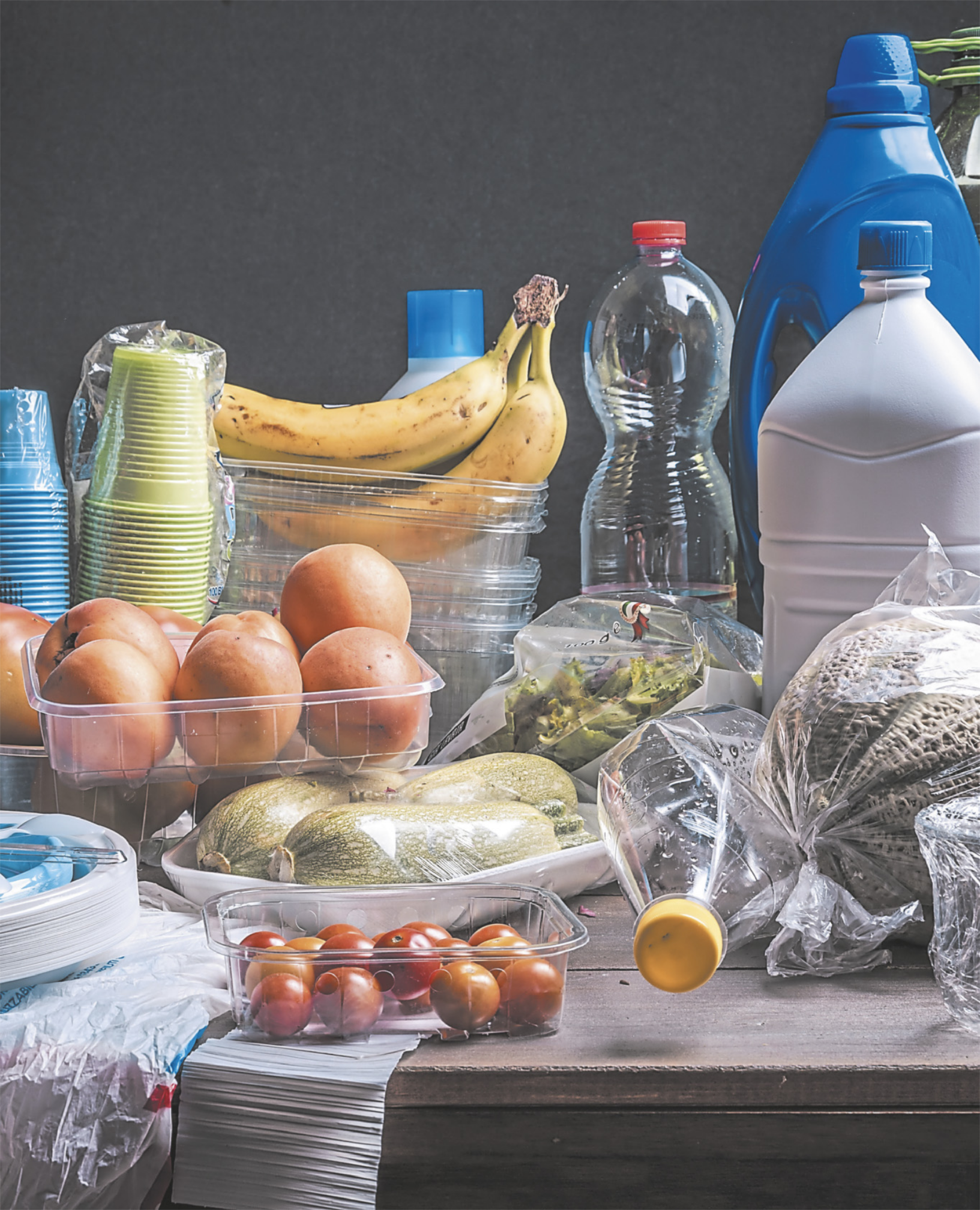 Fotografia contendo diversos produtos em embalagens plásticas. Há garrafas PET, copos descartáveis e recipientes plásticos, isopor, e sacolas plásticas contendo alimentos.