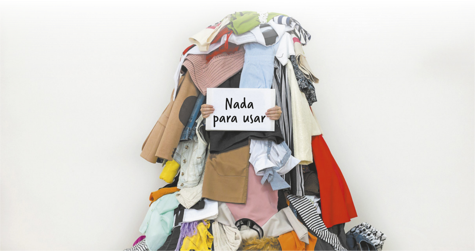 Fotografia de uma pessoa coberta com uma pilha de roupas segurando um cartaz onde está escrito: 'Nada para usar'.