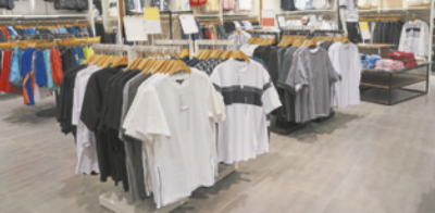 Fotografia de roupas dispostas em cabides e araras de roupa em uma loja.