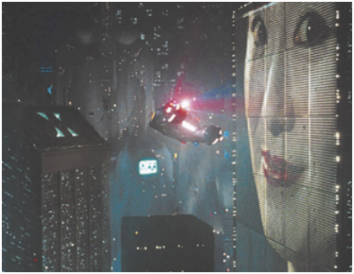 Imagem contendo uma cena do filme Blade Runner. A imagem retrata uma nave espacial voando. Há edifícios e um grande telão com o rosto de uma mulher projetado.