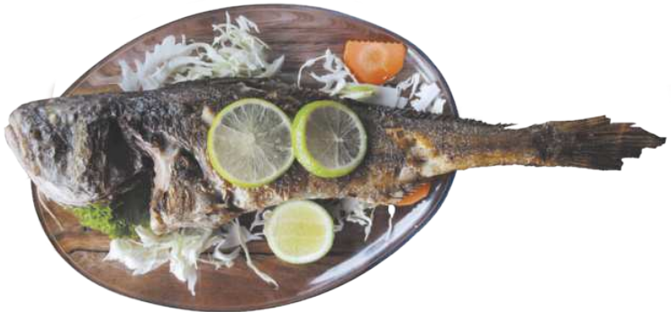 Fotografia de um peixe assado sobre uma tábua, com rodelas de limão sobre ele e alguns legumes ao redor.