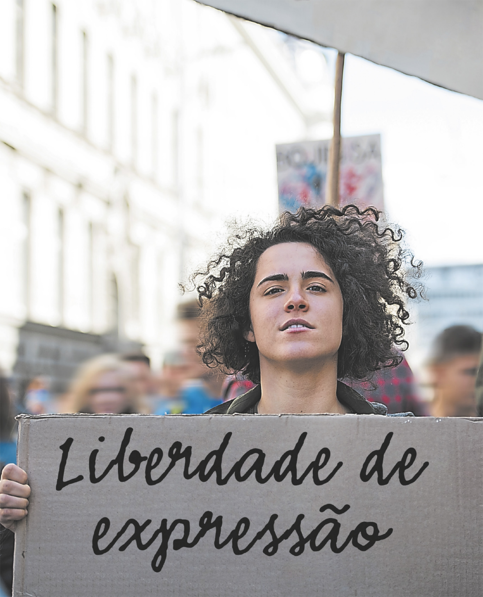 Fotografia de uma mulher participando de uma manifestação de rua, segurando um cartaz com os dizeres 'Liberdade de Expressão'.