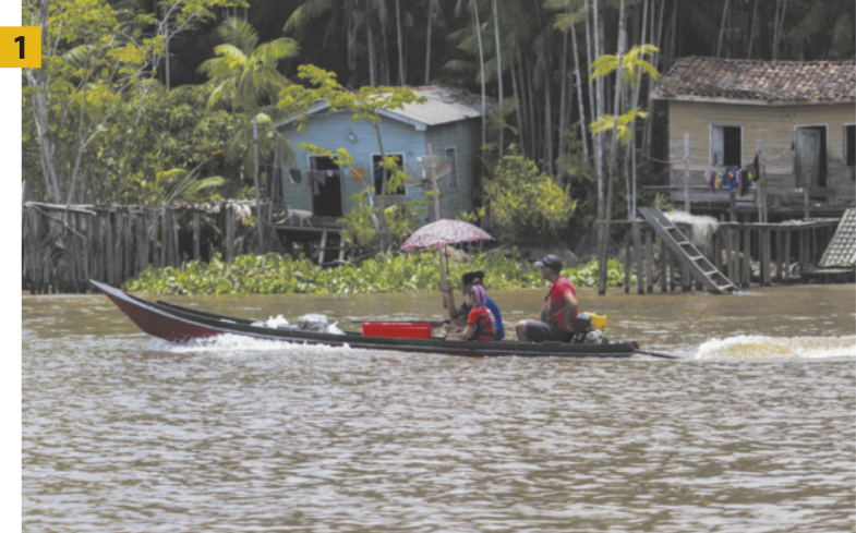 Fotografia 1 apresenta pessoas navegando por um rio em uma canoa motorizada, sendo que uma delas segura uma sombrinha para se proteger do sol. Ao fundo, observa-se uma densa vegetação e casas de palafitas às margens do rio.