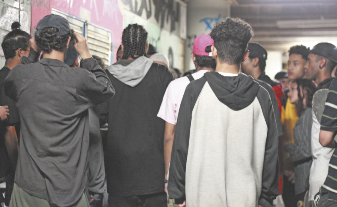 Fotografia de um grupo de jovens reunidos formando uma aglomeração circular na qual eles olham atentamente para o centro.