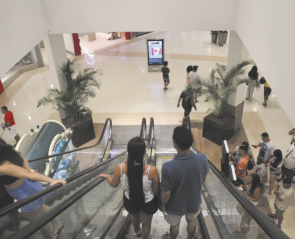 Fotografia de pessoas em uma escada rolante em um shopping.