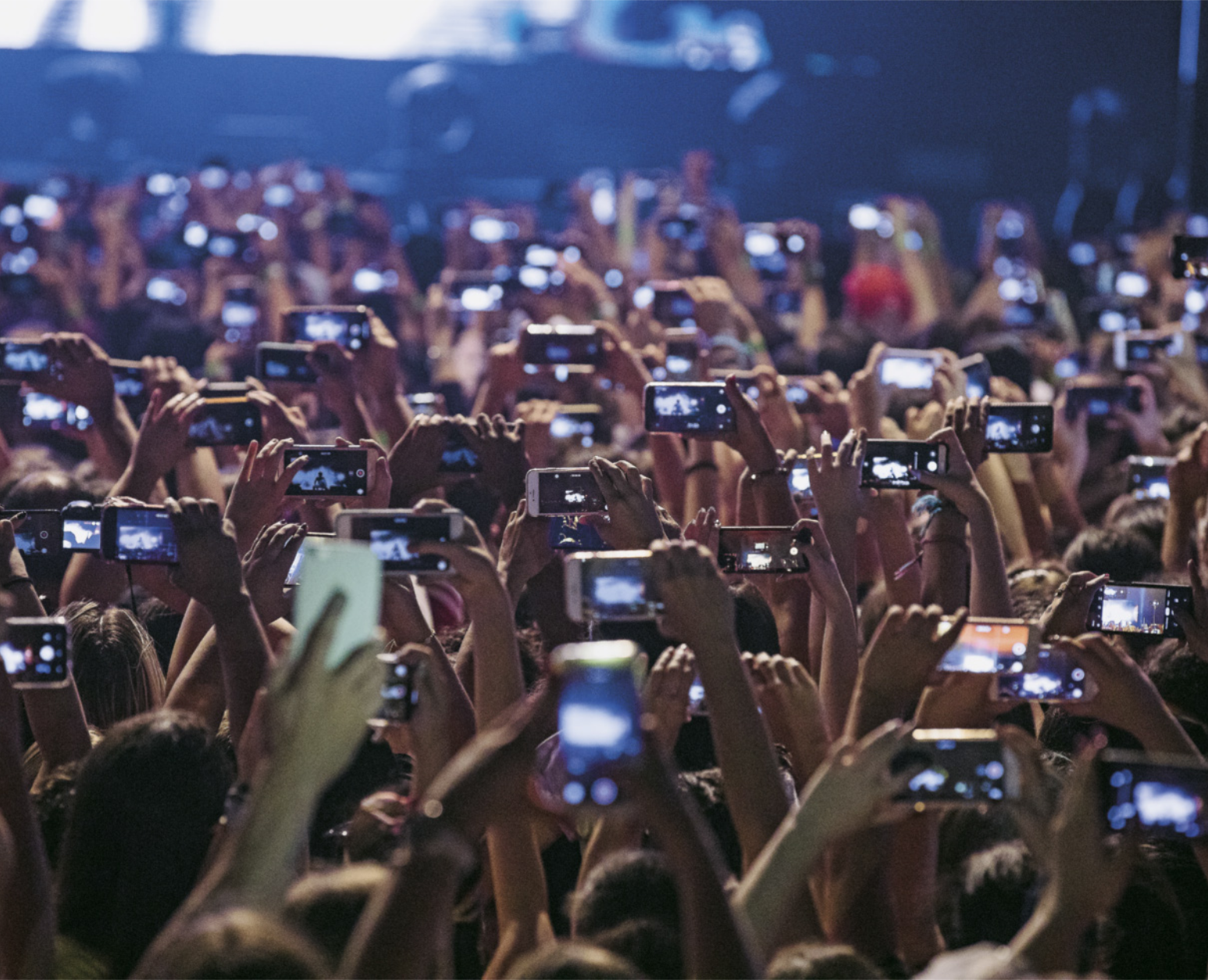Fotografia de um show com a plateia registrando a apresentação com smartphones.