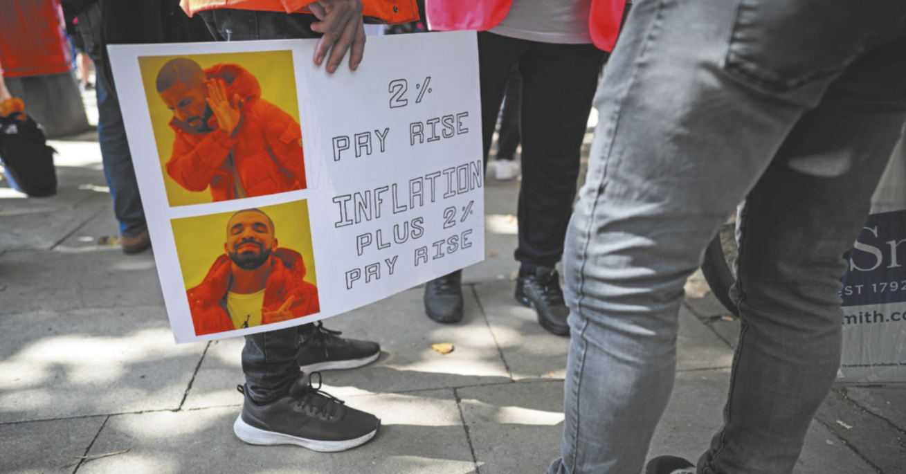 Fotografia de uma pessoa segurando um cartaz com um meme durante uma manifestação de rua.
