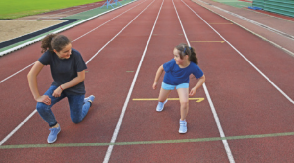 Foto de professora e uma menina em uma pista de corrida.