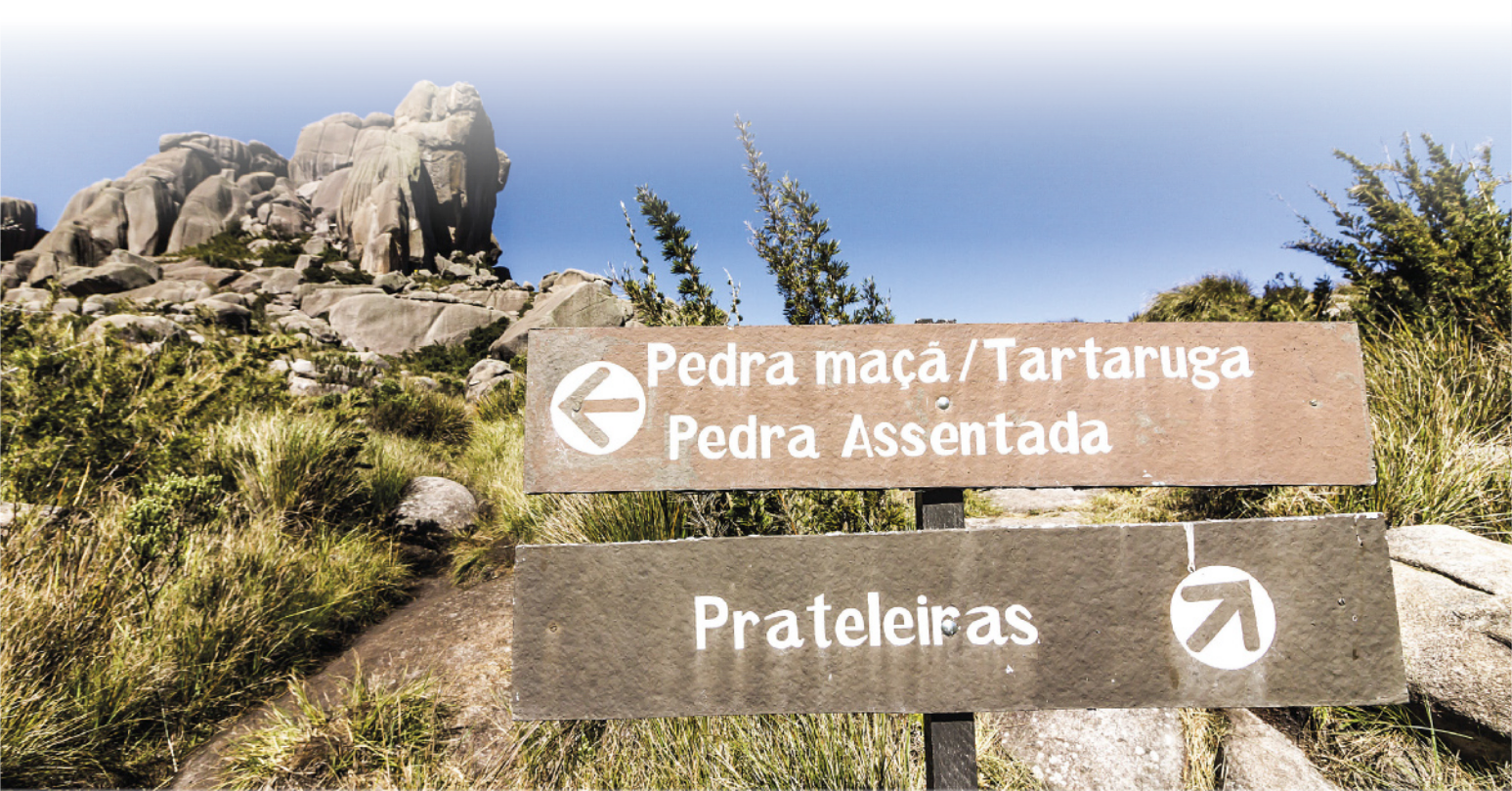 Foto de placas com as seguintes identificações: 'Pedra maçã e tartaruga' e 'Pedra assentada' estão na mesma direção. Para o lado oposto estão as 'Prateleiras'.