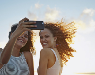 Foto de meninas usando o celular para tirarem uma foto juntas.