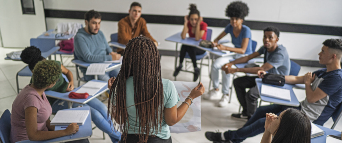 Foto de jovens reunidos em uma sala. Eles estão sentados em roda.