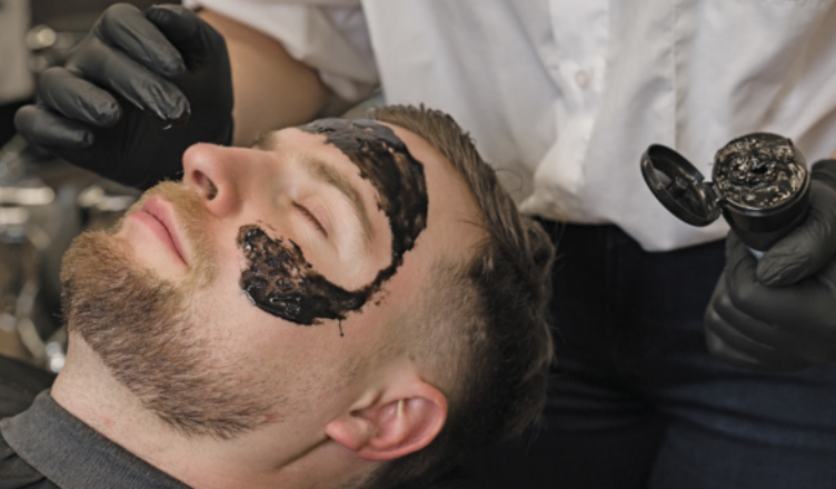 Imagem de pessoa aplicando uma máscara facial em um homem.