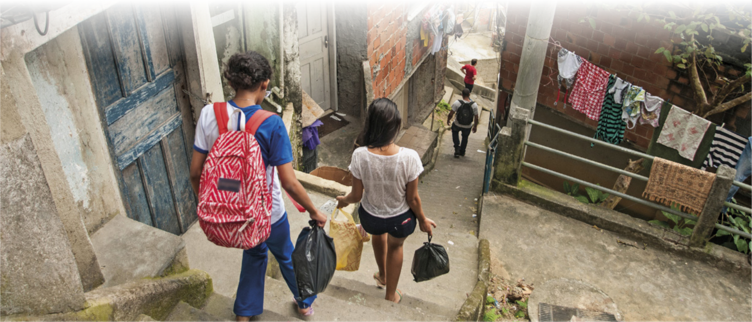 Foto de meninos e meninas descendo uma escada comprida e estreita. Eles carregam mochilas e sacolas plásticas.